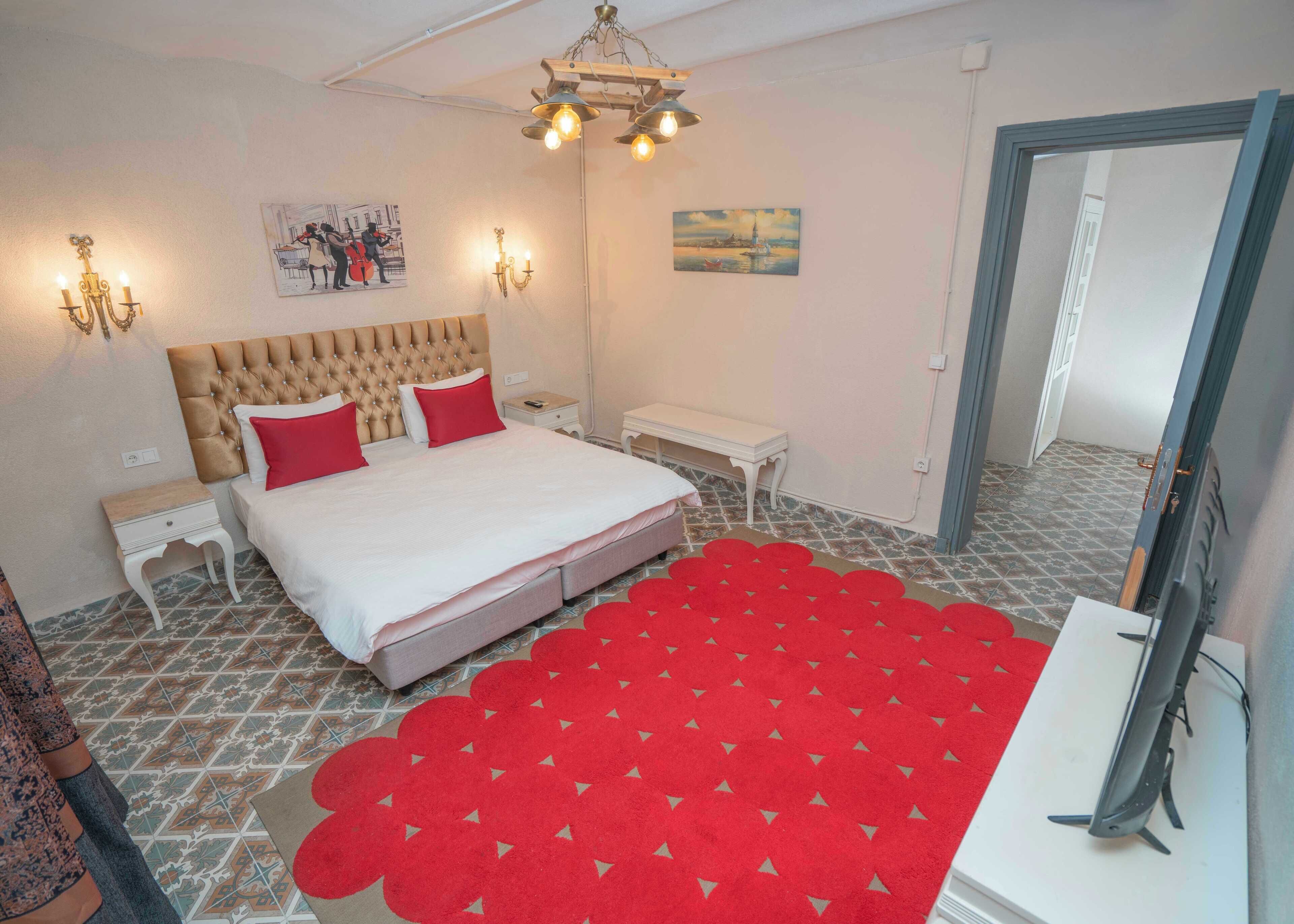 A bedroom with a large bed, a red carpet, a wooden headboard, and a painting on the wall.