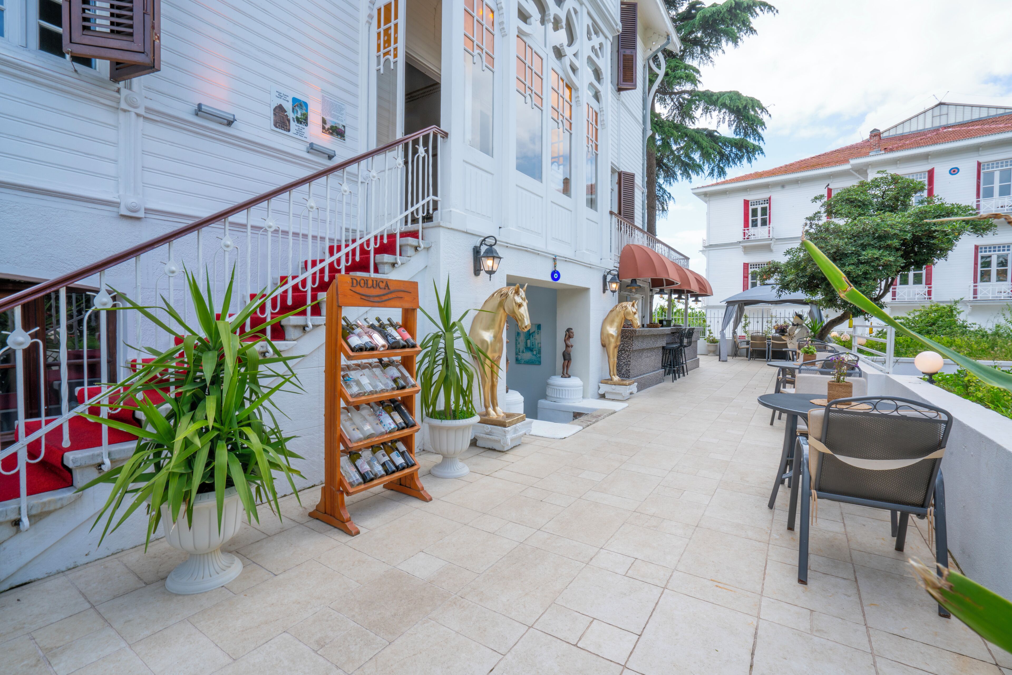 A hotel with a staircase leading to a balcony, outdoor seating area, and a sign for 'Dolcica'.