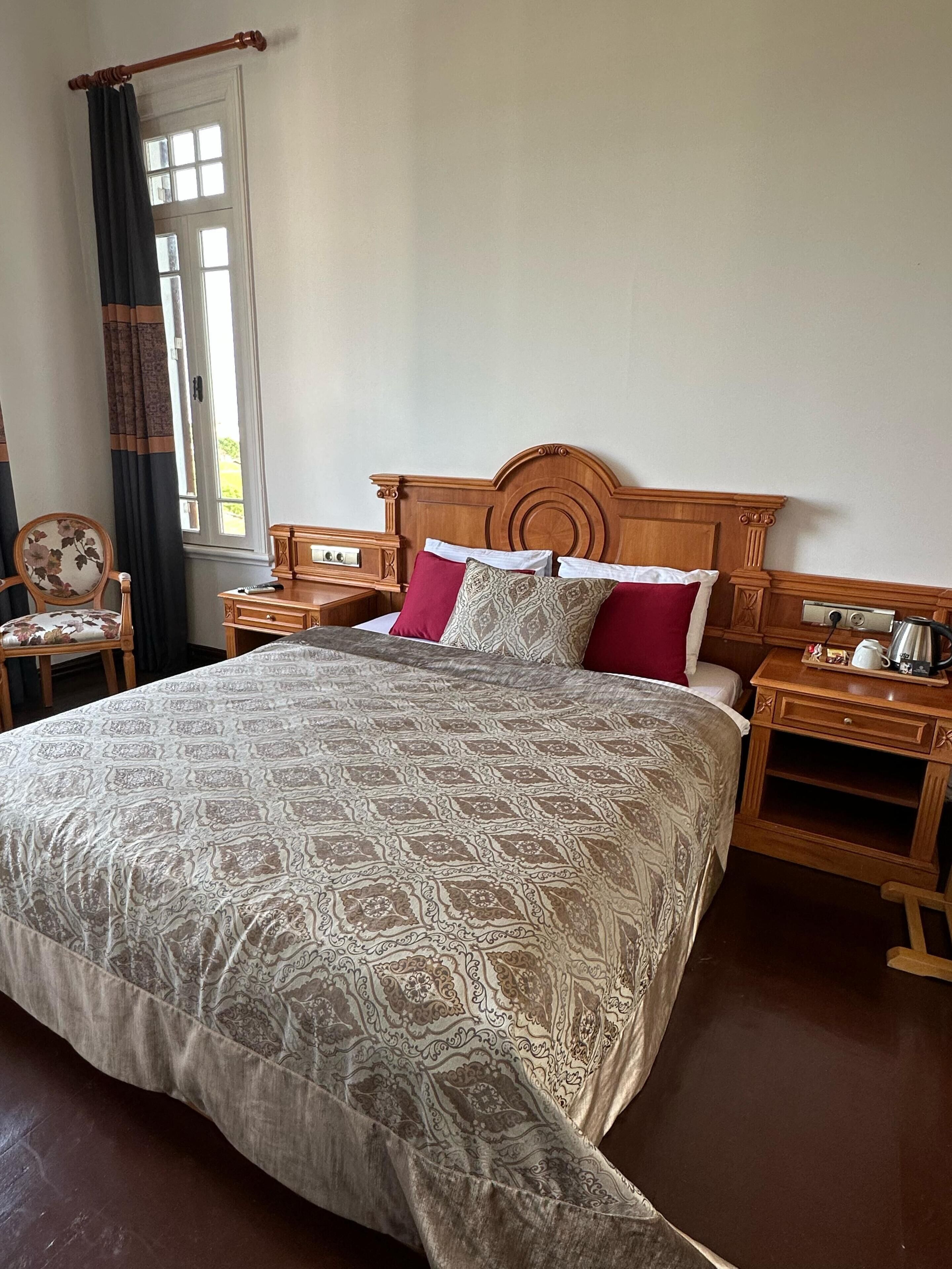 A large bed with a patterned bedspread, wooden headboard, and two bedside tables with lamps.