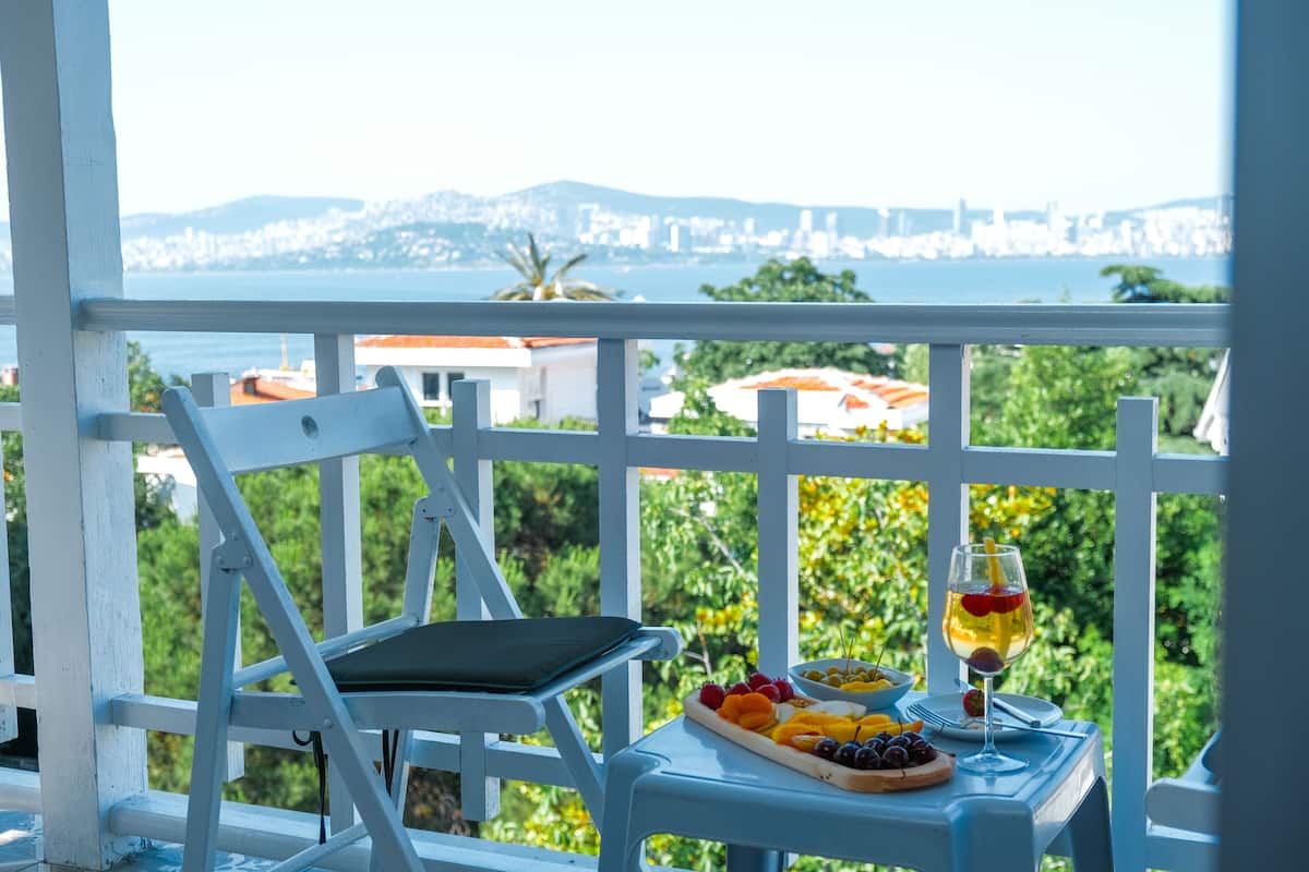 A balcony with a table set for a meal, a glass of drink, and a view of a cityscape.