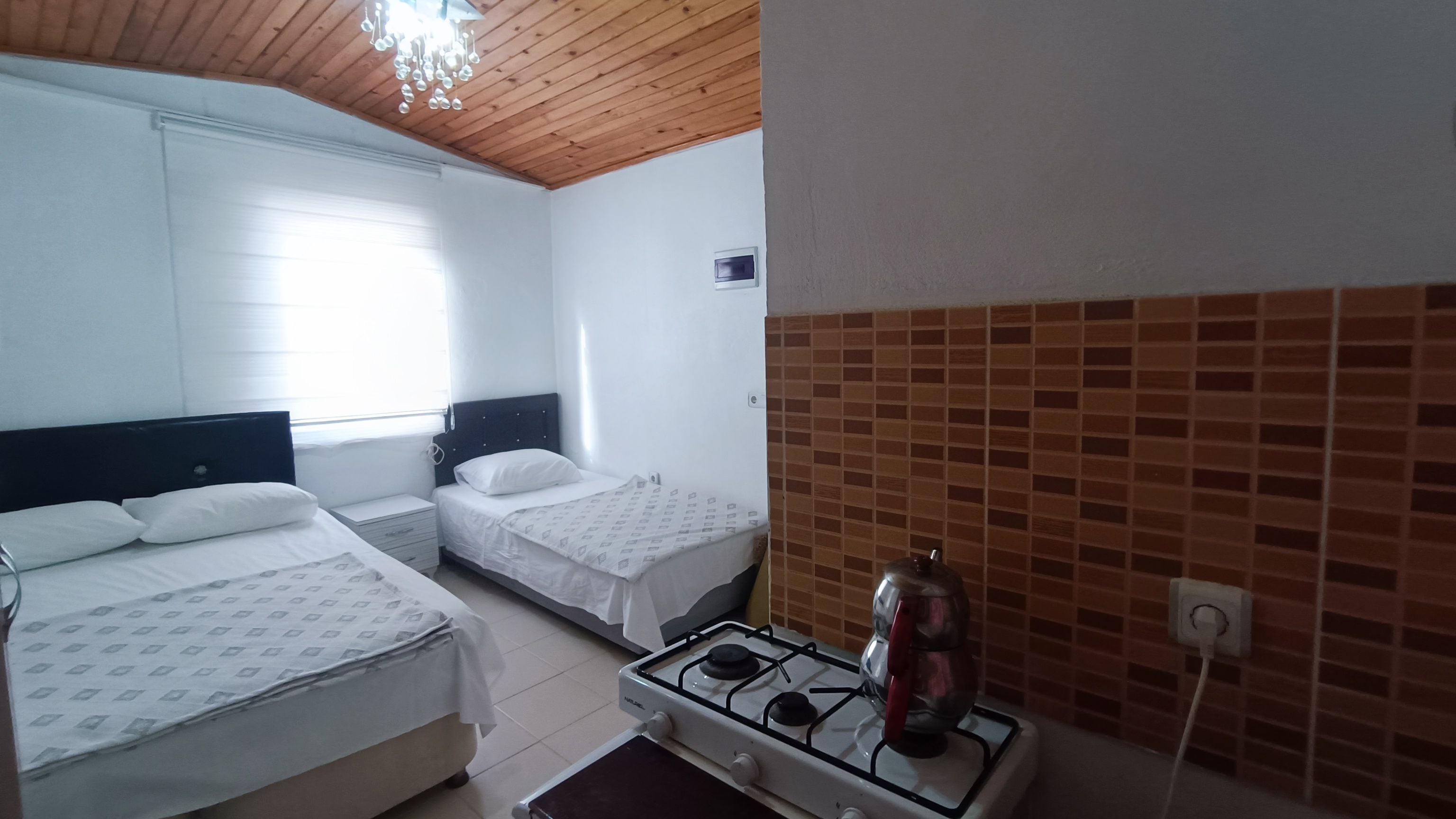 Habitación de hotel con dos camas, estufa a gas y ventana con persianas.