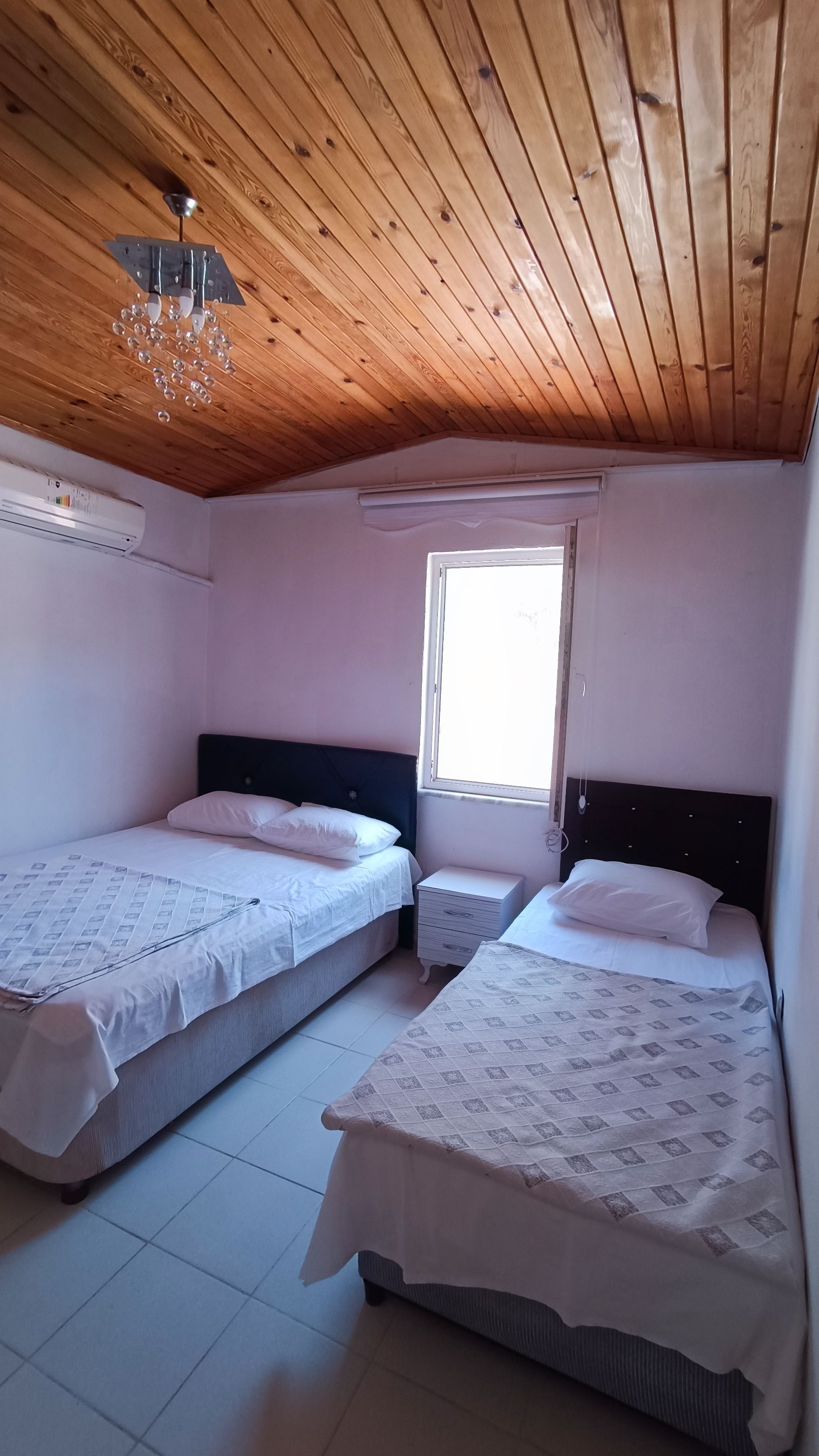 Un dormitorio con dos camas, una ventana y techo de madera.