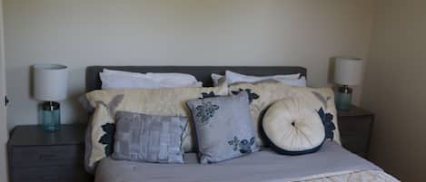 A neatly made bed with a floral-patterned bedspread, two bedside tables with lamps, and a wall with a subtle textured pattern.