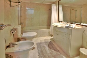 Un bagno dotato di vasca, due lavandini, un water e una doccia.