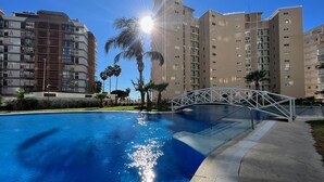 Una piscina con un puente, rodeada de edificios residenciales altos.