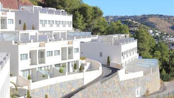Un hotel moderno de varios pisos con un camino curvo y muros de piedra.