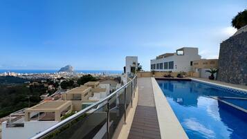 A rooftop pool with a clear view of the cityscape and a prominent mountain in the distance.