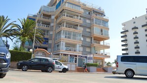A multi-story hotel with balconies, a travel agency, and palm trees. - Alq 156 Talima sea views (Calpe)
