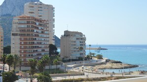A coastal urban area with multi-story buildings, a beach promenade, and a rocky outcrop in the background. - Alq 156 Talima sea views (Calpe)