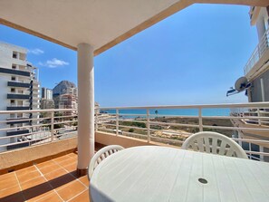 A balcony with a view of the beach, a white table, and a chair. - Alq 156 Talima sea views (Calpe)
