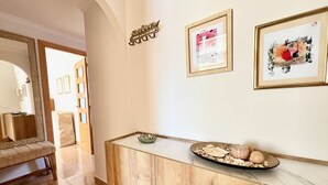 A hallway with a wooden console table, a mirror, and framed artwork on the wall. - Alq 043 Porto Azul 4 (Calpe)