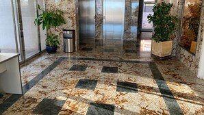 A lobby with a marble floor, two elevators, and potted plants. - Alq 043 Porto Azul 4 (Calpe)
