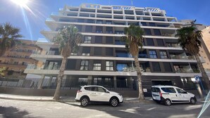 Un immeuble à plusieurs étages doté de balcons et d’un espace de stationnement.