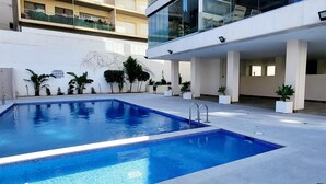 Une piscine intérieure moderne, avec une eau d’un bleu limpide, entourée de plantes en pot et dotée d’une architecture minimaliste.