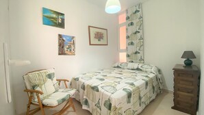 Une chambre à coucher comprenant un lit, une chaise, une commode et des œuvres d’art murales.