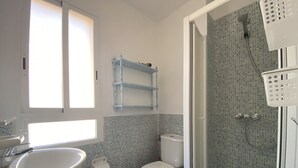 Une salle de bain avec des toilettes, un lavabo et une douche.
