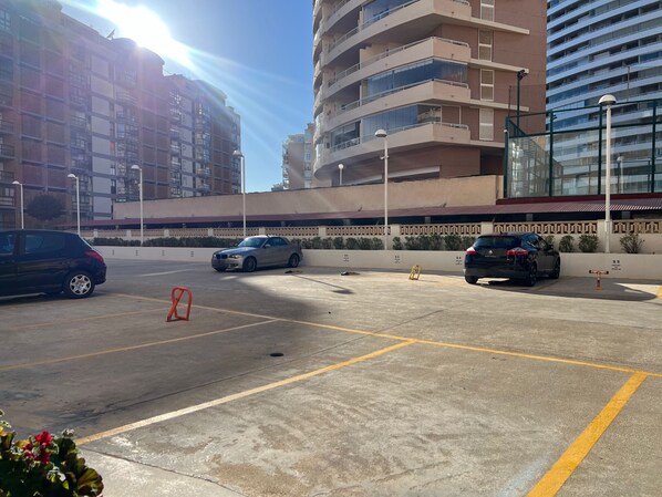 A parking lot with multiple cars, a building with balconies, and a clear sky. - Alq 178 Amatista Apartment (Calpe / Calp)