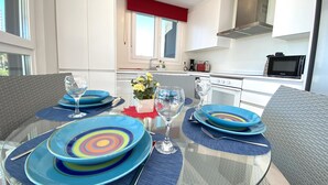 A modern kitchen with white cabinets, a red window valance, and a black microwave.