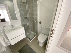 Une salle de bain moderne avec une douche à parois de verre, des toilettes et un lavabo avec un miroir.