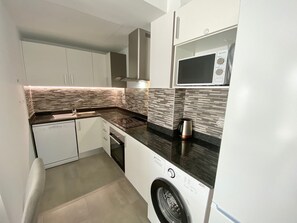 A compact kitchen with a washing machine, a microwave, and a sink. - Alq 229 Calpe Beach (Calpe / Calp)