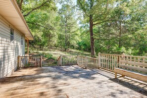 A wooden deck with a wooden bench and a railing, surrounded by trees. - Peaceful Alabama Vacation Rental w/ Large Deck (Jackson)