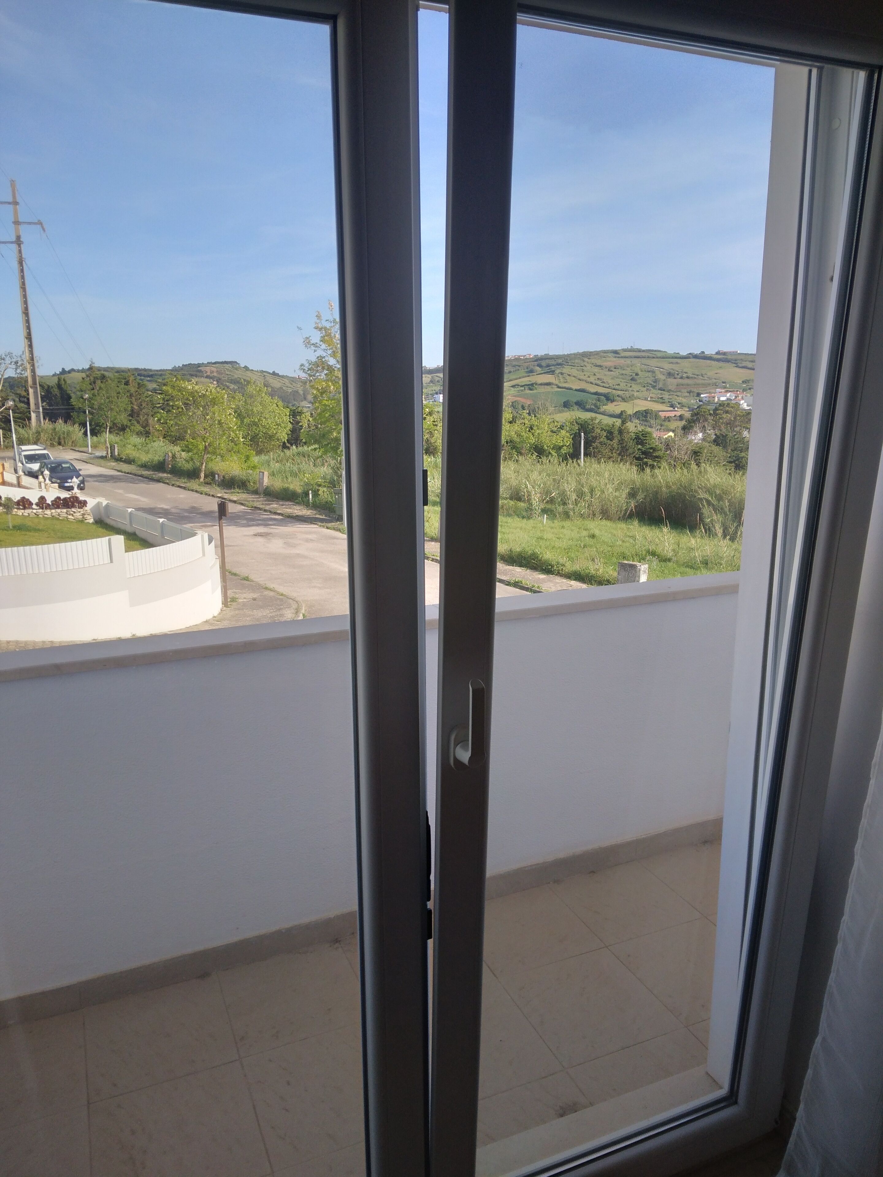 A balcony with a view of a road and greenery.