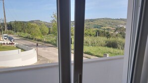 A balcony with a view of a road and greenery.