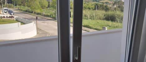 A balcony with a view of a road and greenery.