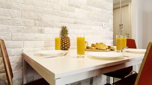 Un desayuno con una mesa blanca, dos vasos de jugo de naranja, una piña y un plato de croissants.