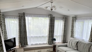 A modern living room with a sofa, TV, and dining area. - CS 53 - Vakantiepark Callassande (Callantsoog)