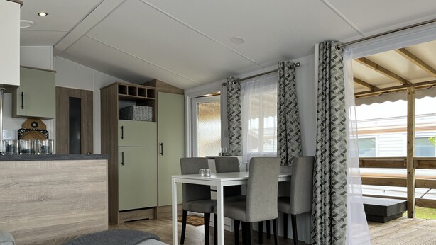 A compact living space with a kitchenette, dining area, and a sofa. - CS 53 - Vakantiepark Callassande (Callantsoog)