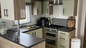 A compact kitchen with a central island, built-in oven, and stainless steel appliances. - CS 53 - Vakantiepark Callassande (Callantsoog)
