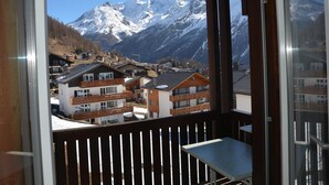 A balcony with a view of snow-covered mountains and a town below. - Topas 24 by Interhome (Saas-Fee)