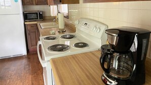 Une cuisine avec des meubles en bois, un four blanc, un four à micro-ondes et une machine à café.