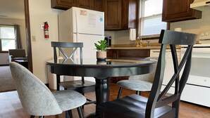 Une cuisine moderne avec des meubles en bois, un réfrigérateur, une cuisinière et une table à manger avec quatre chaises.