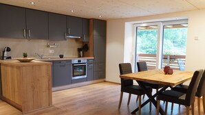 Una cocina moderna con gabinetes grises, una isla de madera y un comedor con una mesa y sillas de madera.