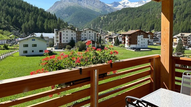 Un balcón de madera con vista a una montaña y un complejo hotelero.