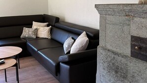 Una sala de estar moderna con un sofá de cuero negro, una mesita redonda y una chimenea de piedra.