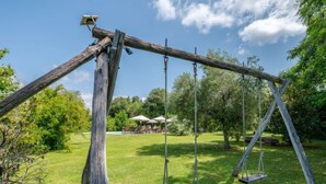 Een houten schommel in een gazon onder een heldere lucht.