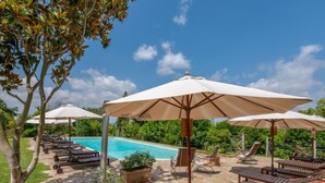 Un espace aménagé au bord de la piscine, avec des chaises longues, des parasols et des plantes en pot.