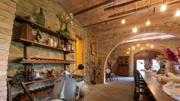 Un intérieur rustique avec des murs en pierre, des étagères en bois et un scooter vintage.