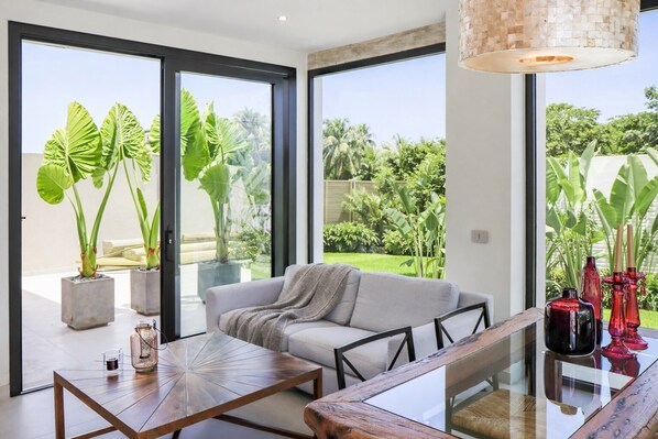 A modern living room with a sofa, coffee table, and potted plants.