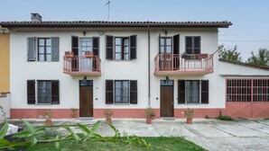 A two-story building with balconies, a red door, and potted plants in the front yard. - Casa dei Nonni by Interhome (Calliano)