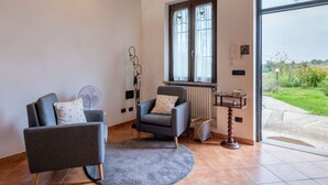 A living room with two grey armchairs, a small round rug, a radiator, and a window with curtains. - Casa dei Nonni by Interhome (Calliano)