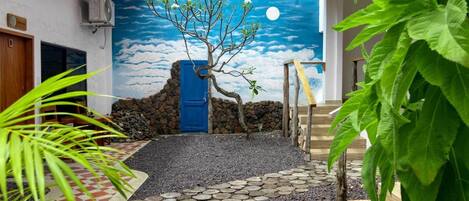 A courtyard with a tree, a blue door, and a stone pathway.