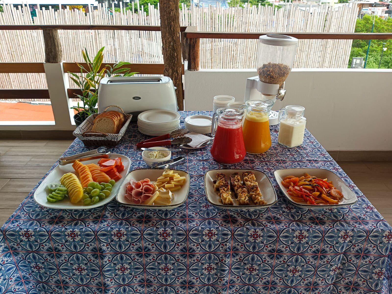 A breakfast buffet with various food items and beverages on a table with a patterned tablecloth.