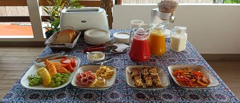 A breakfast buffet with various food items and beverages on a table with a patterned tablecloth.