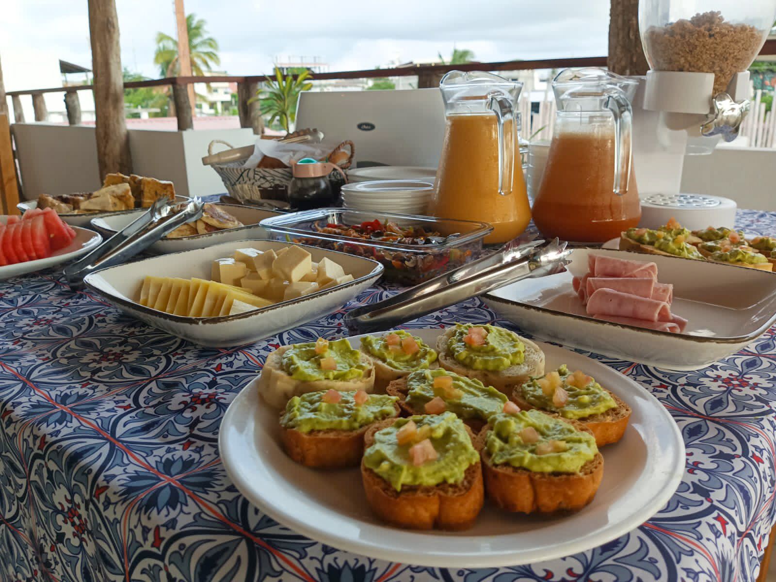 Une table de buffet proposant divers plats et un distributeur de jus de fruits.