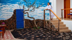 Una escalera con barandas de madera, un muro de piedra y una puerta azul.