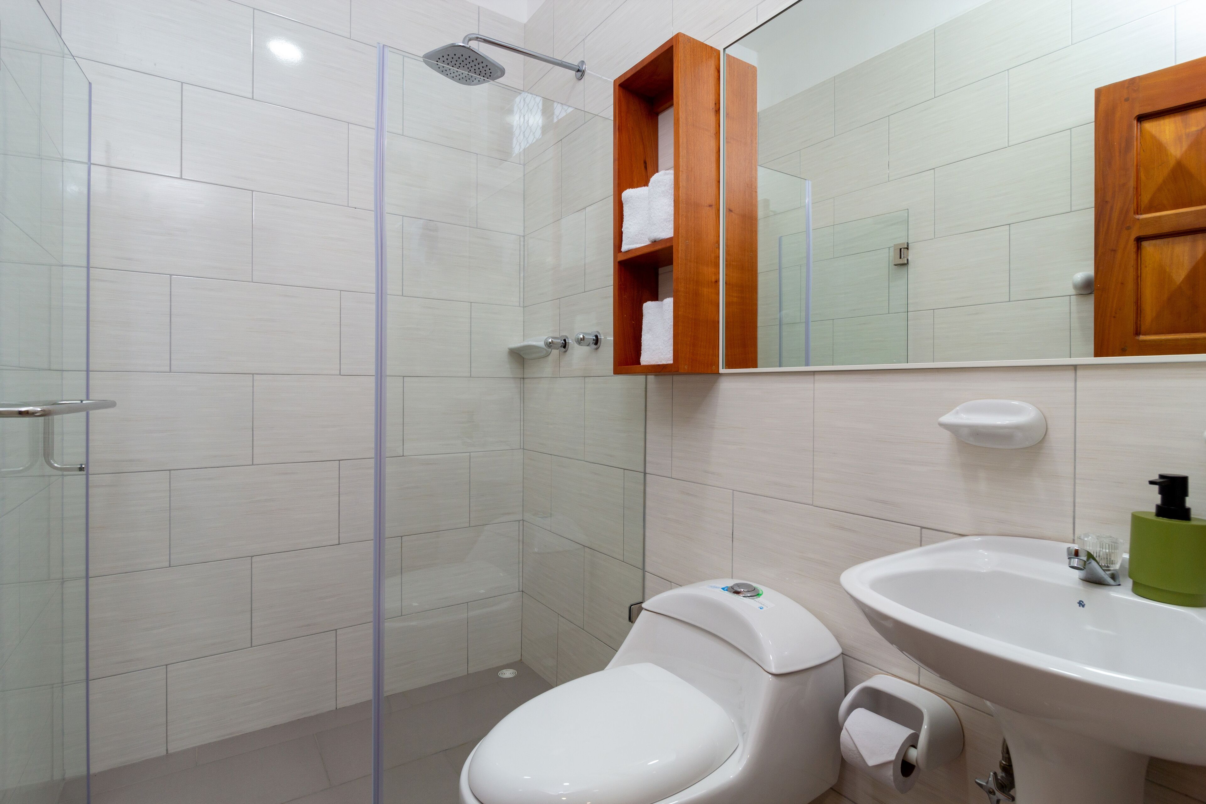 Une salle de bain moderne avec une douche à parois de verre, des toilettes, un lavabo et un meuble à pharmacie en bois.
